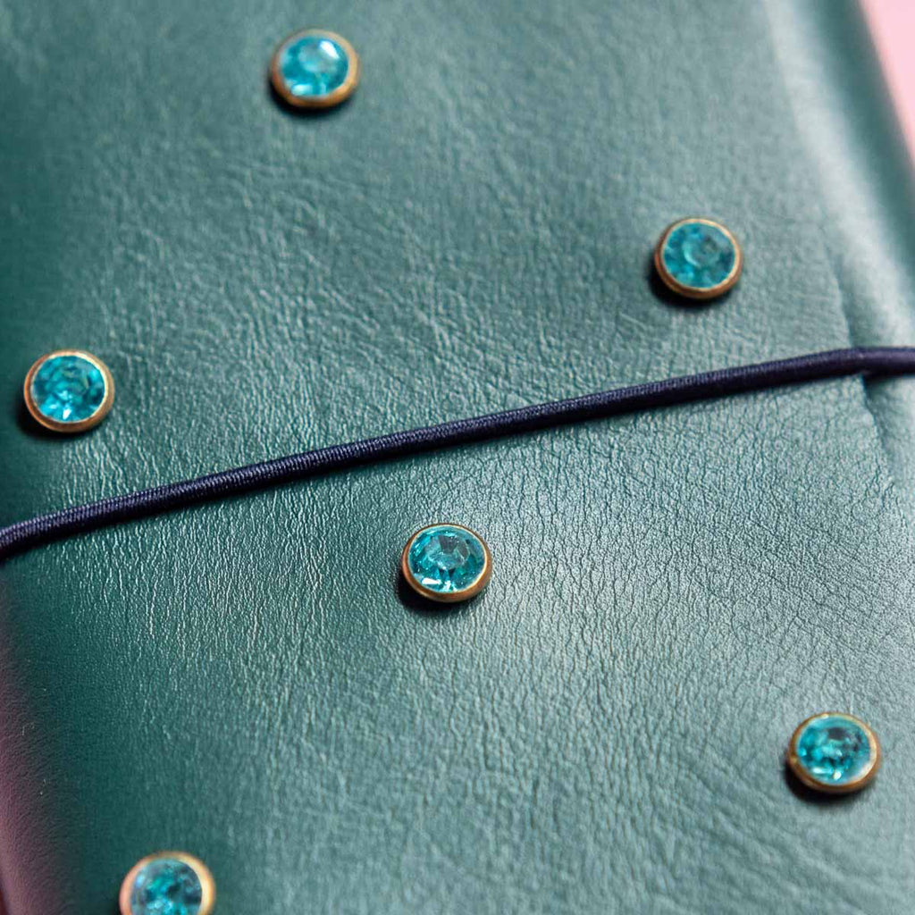Close-up of a green leather journal with turquoise gemstone buttons.