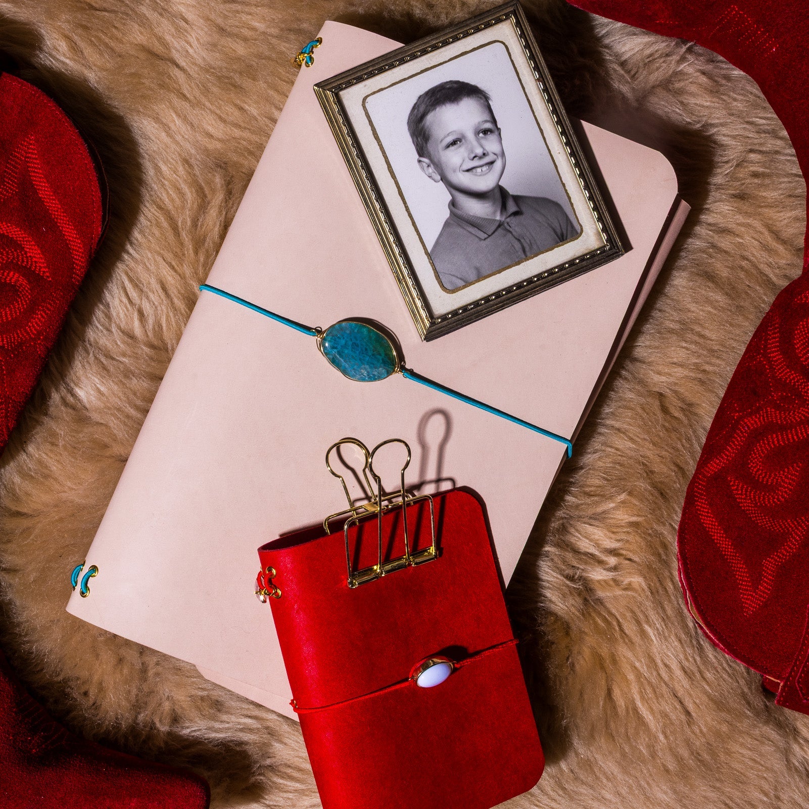 Red suitcase with a photo of a child on a notebook, all on a fur surface.